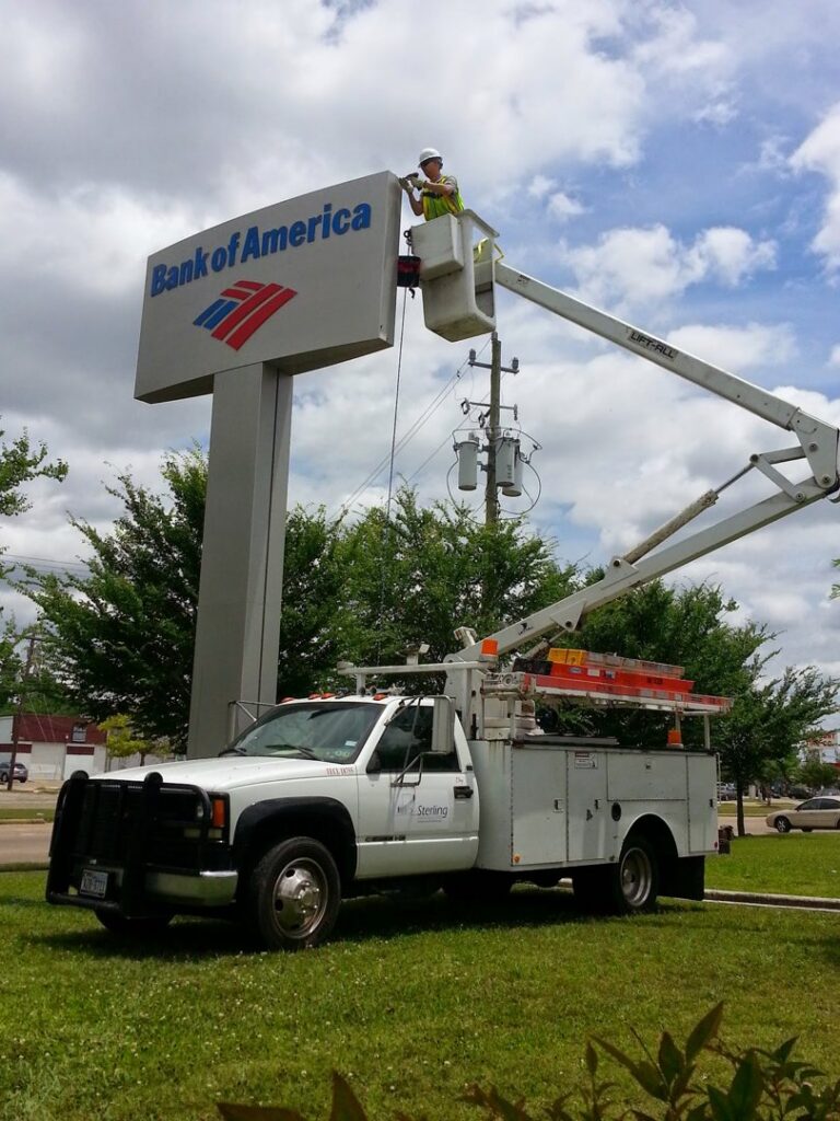 An electrician in a bucket truck performing electrical work on a Bank of America sign for Sterling Wiring Solutions in Pearland, TX.