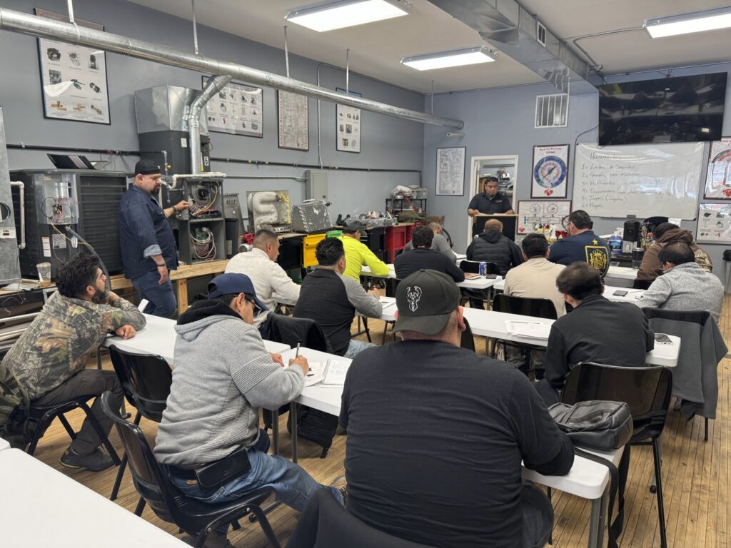 An electrician classroom with students seated at desks and electrical training panels visible on the wall at Escuela Tecnica ABC in North Chicago, IL
