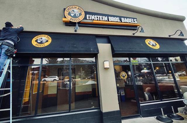 An electrician on a ladder performing commercial sign repair for Black Bear Electric in Aurora, CO.