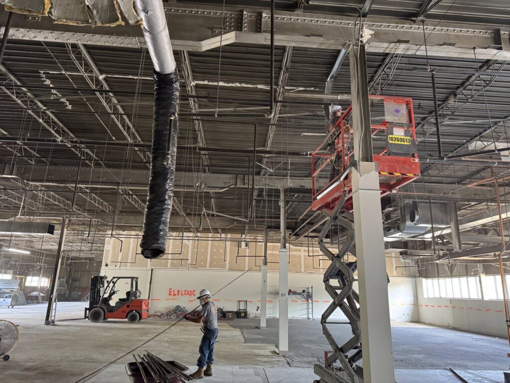 An electrician on a scissor lift installing commercial wiring in a large space for Ramos Electrical services inc in Brownsville, TX