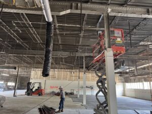 An electrician on a scissor lift installing commercial wiring in a large space for Ramos Electrical services inc in Brownsville, TX