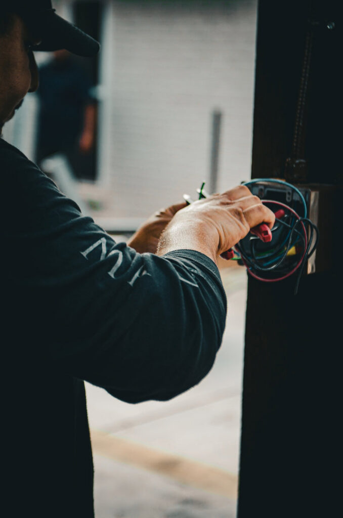An electrician from Mattox Electric, LLC in Dallas, TX, expertly connecting wires inside an electrical box during an installation.