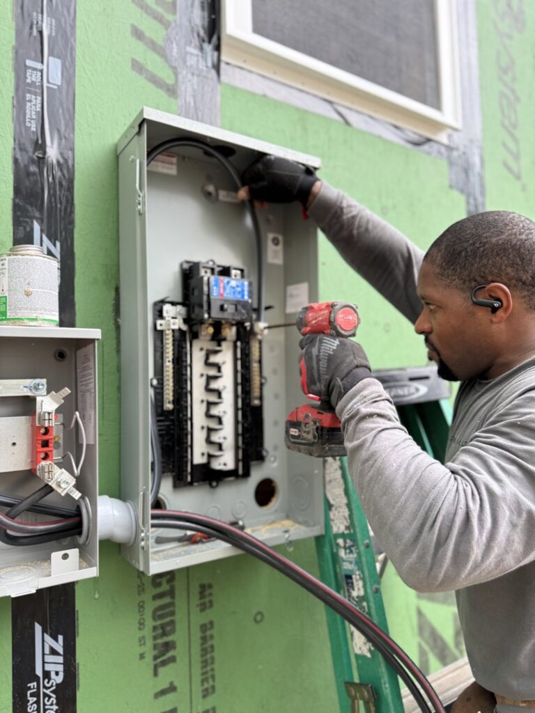 An electrician from Green Volt Electric LLC connecting wires in an outdoor electrical panel in Durham, NC.