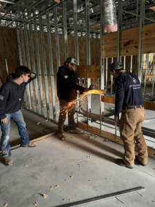 An electrician from Stroh Electrical cutting metal conduit or studs with a grinder at a construction site in Montgomery, AL.