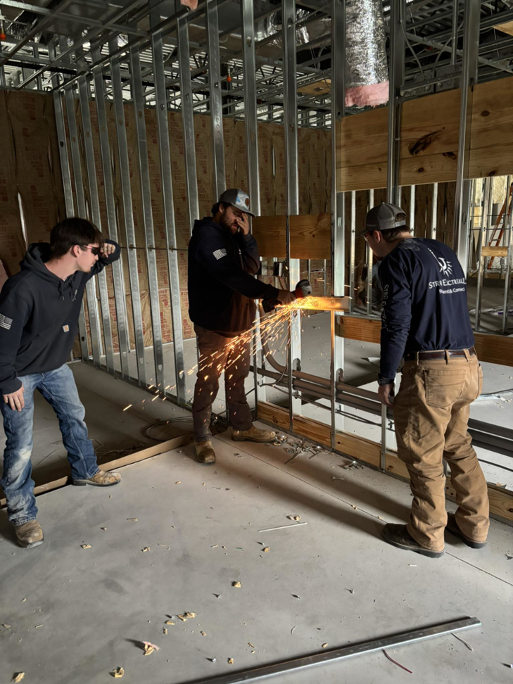 An electrician from Stroh Electrical cutting metal conduit or studs with a grinder at a construction site in Montgomery, AL.