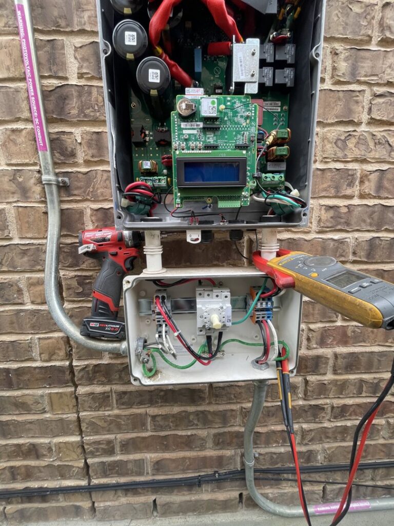An electrician diagnosing an open electrical inverter or control box with a multimeter for Rubio Electrical Innovations LLC in San Antonio, TX.