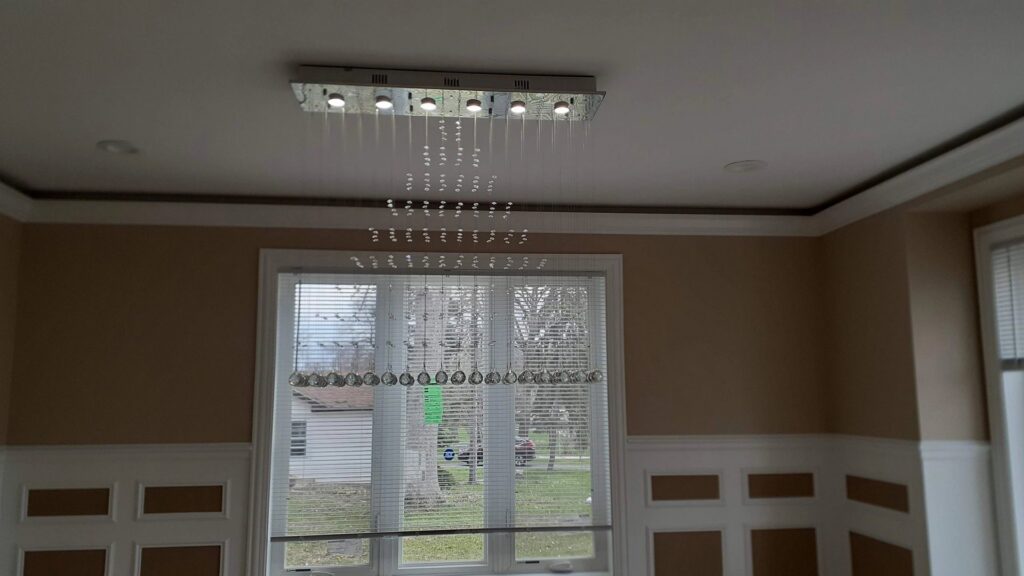An electrician from Neighborhood Electric drilling into a wall during a Ford EV charger installation in West Chicago, IL.