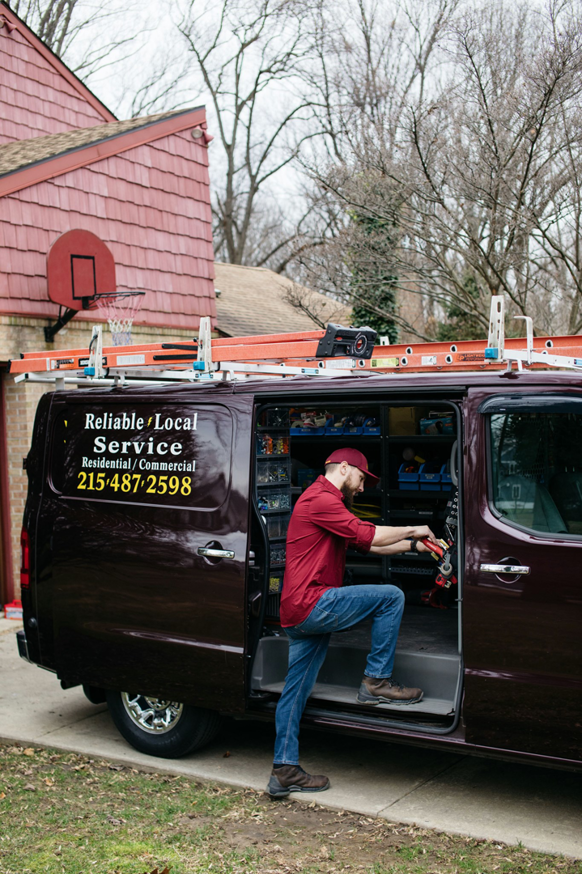An electrician from John Fean Electrician Inc. entering his service van with ladders in Philadelphia, PA.