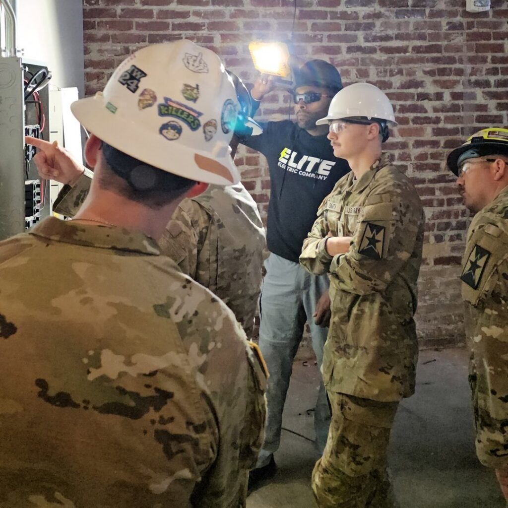 An Elite Electric Company electrician explaining or working on an electrical panel to a group of observers in Melrose Park, IL