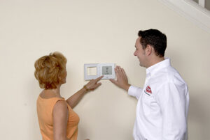 An electrician from Kelly Heating & Electric, LLC explaining a new thermostat to a customer in Eau Claire, WI.