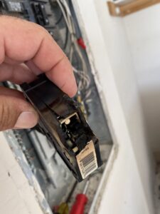 An electrician holding a burnt circuit breaker, indicating a need for electrical repair by Phoenix Electric, Inc. in Cape Coral, FL