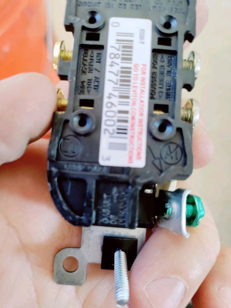 An electrician holding an electrical outlet, showing the wiring terminals, for a job by Johnson Power and Air in Gilbert, AZ.