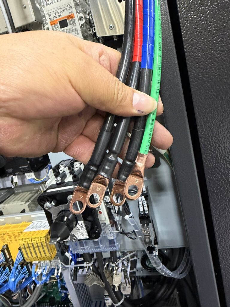 An electrician's hand holding thick electrical wires with terminals for Pioneer Electric LLC in West Valley City, UT.