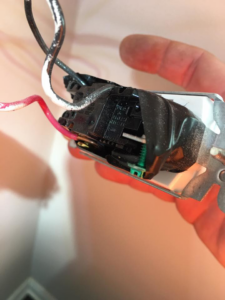 A close-up of an electrician holding a wired light switch during installation by U-R Wired in Baltimore, MD.
