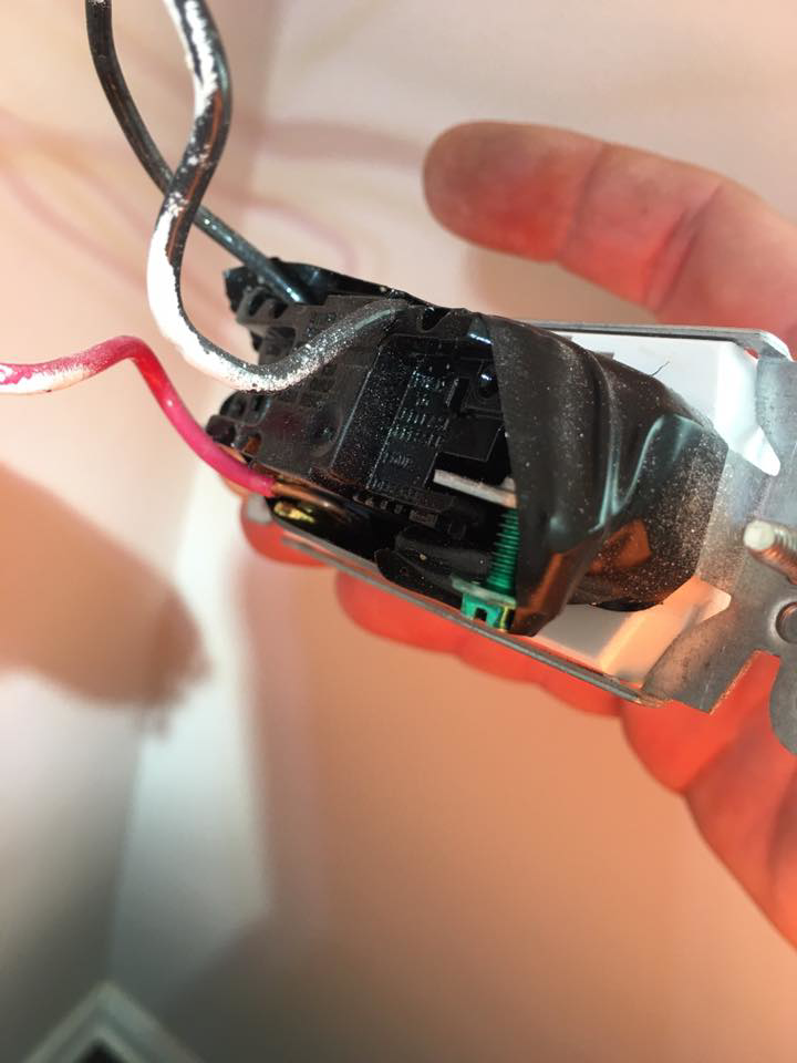 A close-up of an electrician holding a wired light switch during installation by U-R Wired in Baltimore, MD.