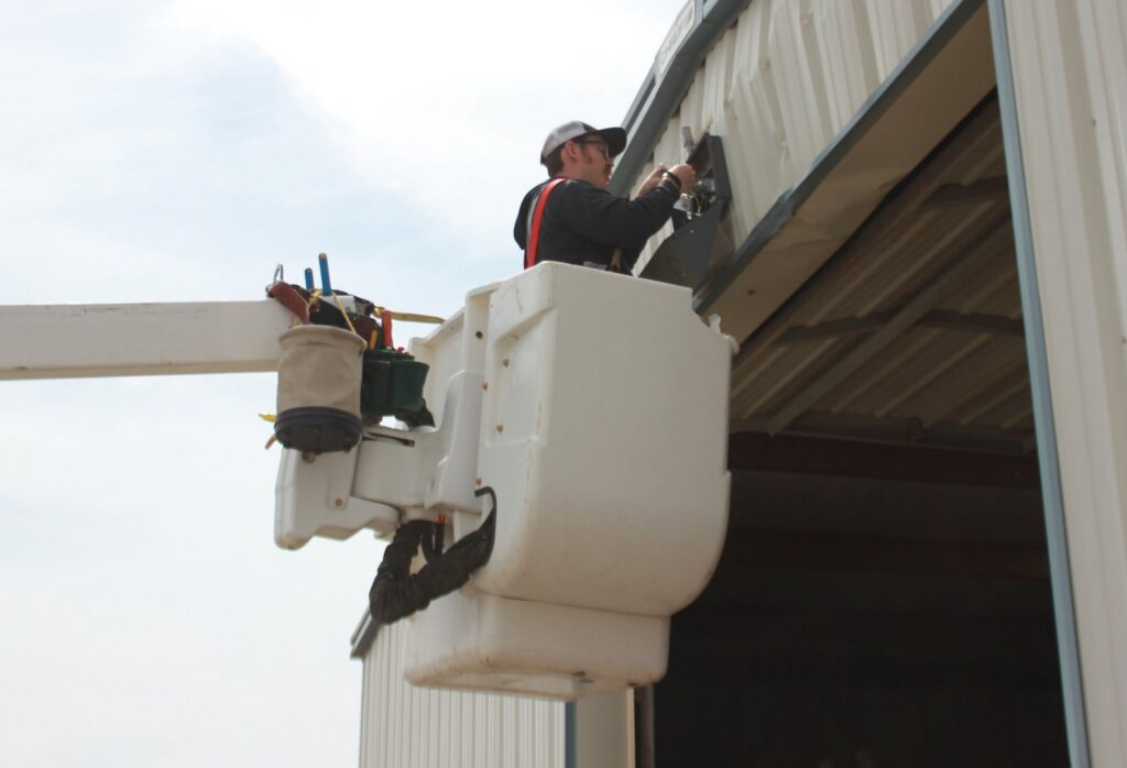 An electrician in a bucket lift working on exterior wiring or a fixture for Robert's Electric Inc. in Manhattan, KS