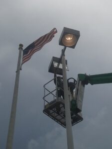 An electrician in a lift bucket working on a tall light pole for Dobson Electric, Inc. in Jacksonville, FL.