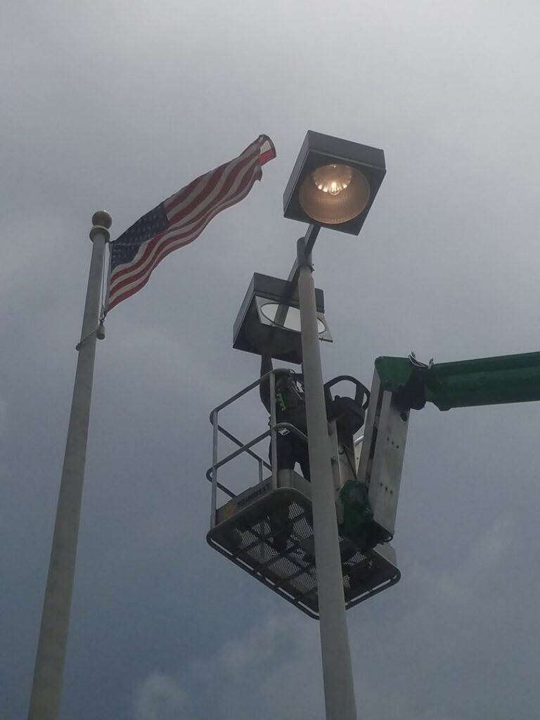 An electrician in a lift bucket working on a tall light pole for Dobson Electric, Inc. in Jacksonville, FL.