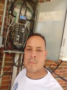 An electrician inspecting an open breaker panel for Illuminate Electric, Inc. in Denver, CO