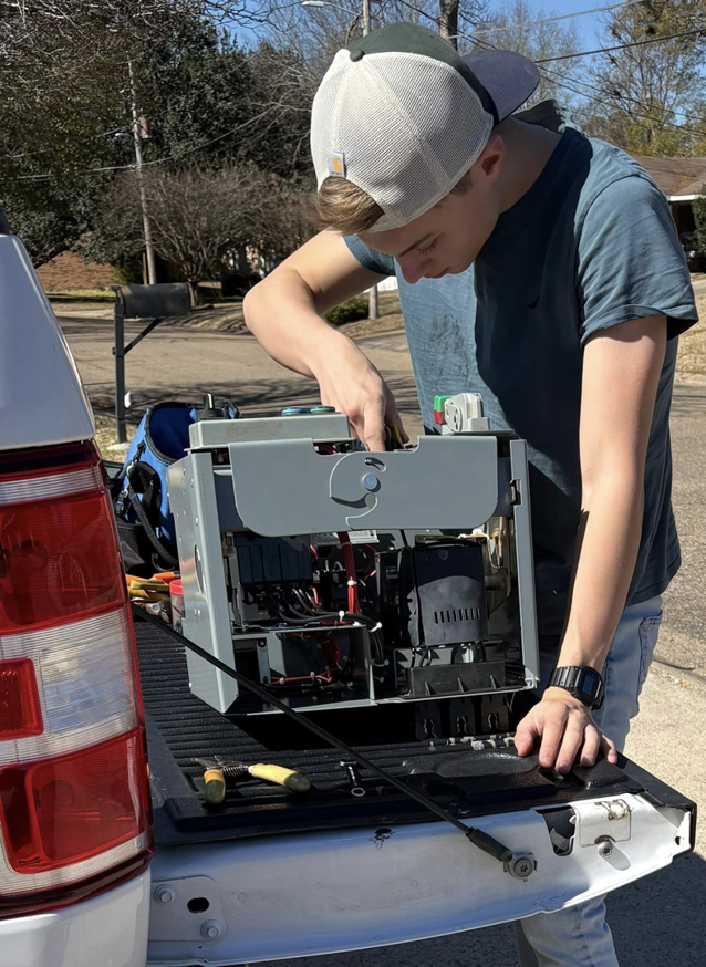 An electrician inspecting an electrical control panel in a truck bed for Prescott Electric Service in Hattiesburg, MS.