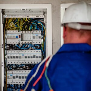 An electrician in a hard hat inspecting an open electrical panel at Generators Sets in Hialeah, FL.