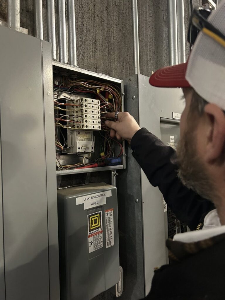 An electrician from Mister Sparky of Greensboro inspecting an open electrical panel in Greensboro, NC.