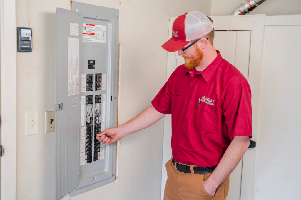 An electrician from Murray Electric & Plumbing inspecting an electrical panel in Broken Arrow, OK.