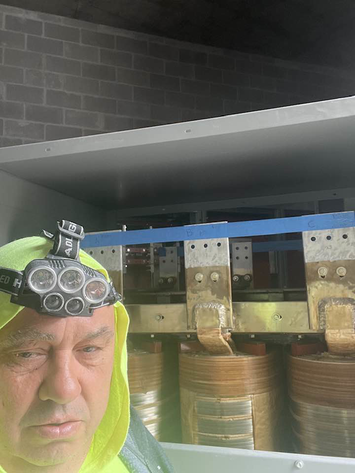 An electrician from Sttrango Electric Company inspecting an open electrical transformer in Chicago, IL.