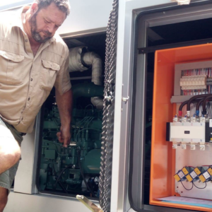 An electrician inspecting a generator and its electrical control panel at WM Elektries & Verkoeling in Dendron, South Africa.