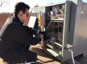 An electrician inspecting the control panel and wiring of an HVAC unit for Cool Aid Air Conditioning in Scottsdale, AZ.