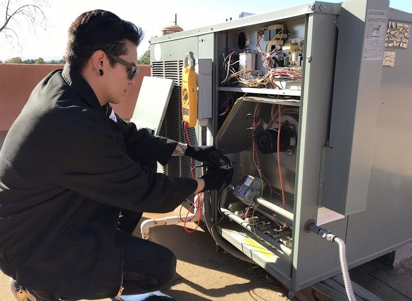 An electrician inspecting the control panel and wiring of an HVAC unit for Cool Aid Air Conditioning in Scottsdale, AZ.
