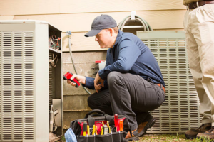 An electrician inspecting an outdoor HVAC unit with a diagnostic tool at Andrews Electric Services in Knoxville, TN