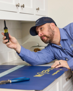 An electrician inspecting wiring under a kitchen cabinet for a client of Mr. Electric of Tulsa - Metro in Tulsa, OK.