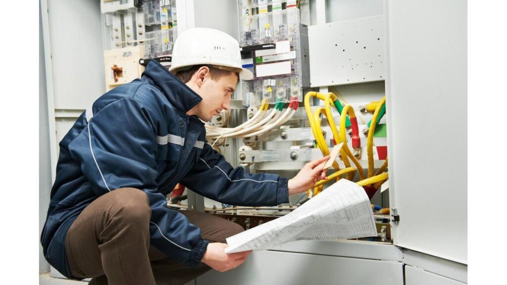 An electrician in a hard hat inspecting an electrical panel with wiring diagrams for BrotherlyLove Electric LLC in Houston, TX.