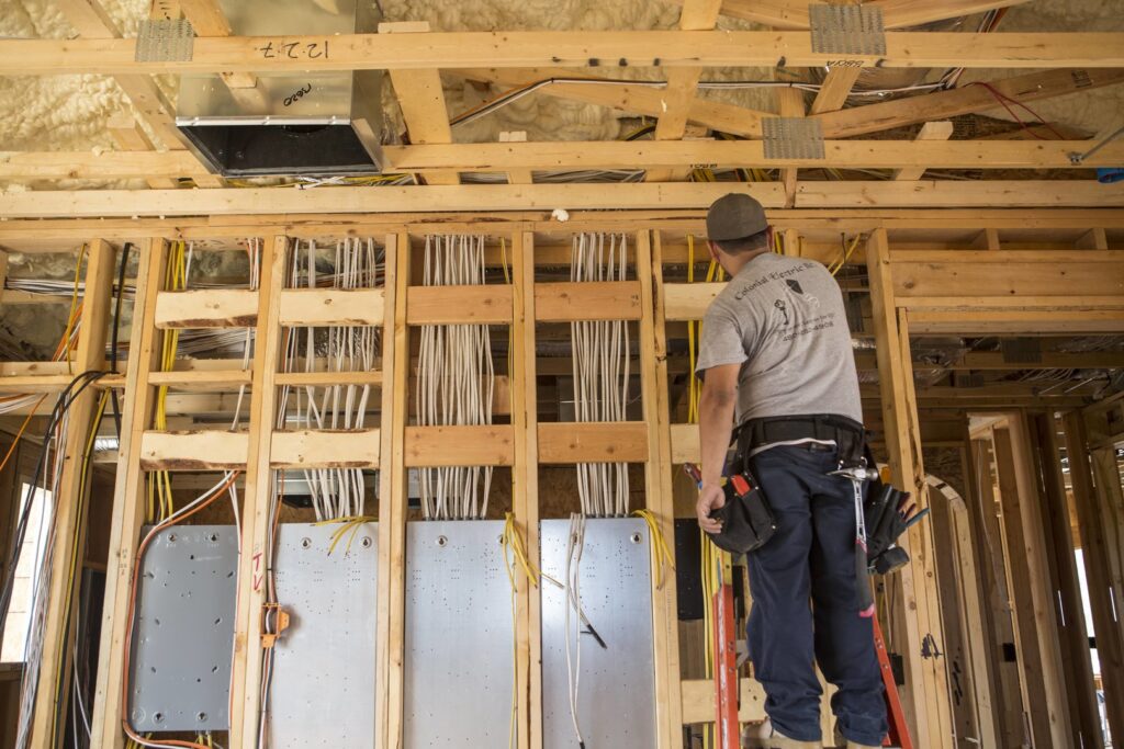 An electrician inspecting rough-in electrical wiring and panels in a new build for Colonial Electric LLC in Scottsdale, AZ.