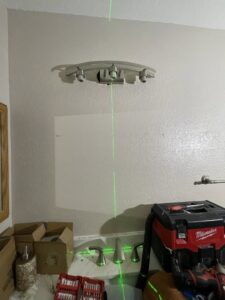 An electrician using a laser level to install a bathroom light fixture for Rogers Family Handyman in Chandler, AZ