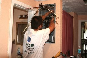 An electrician from Ace Electrical Services installing or repairing a breaker panel in Jacksonville, FL.