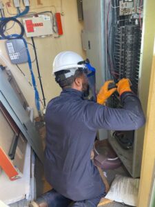 An electrician in safety gear installing a breaker panel for AVA Electric, LLC in Fort Worth, TX.