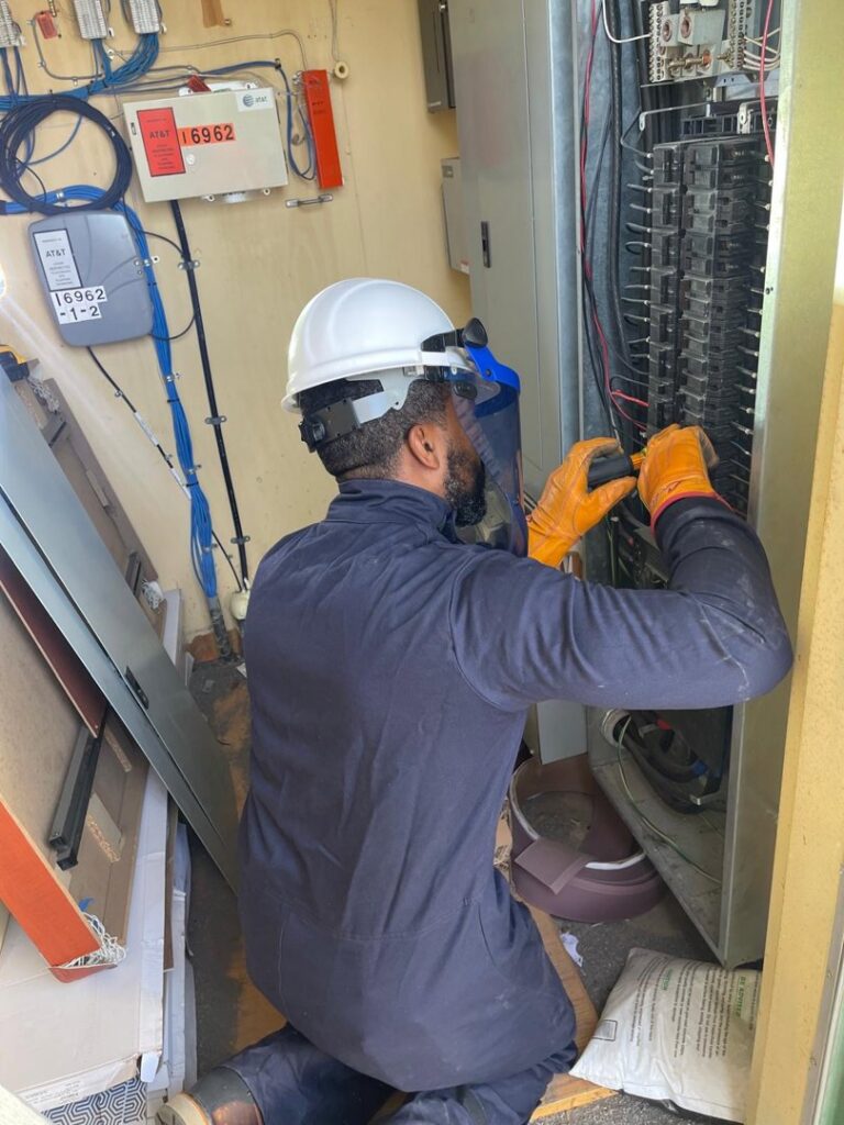 An electrician in safety gear installing a breaker panel for AVA Electric, LLC in Fort Worth, TX.