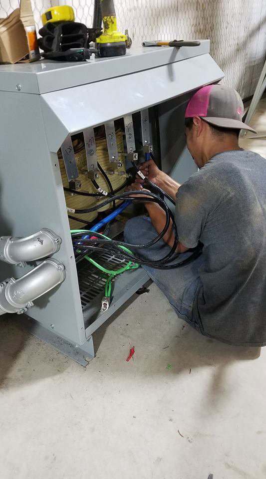 An electrician from Mario Electric installing heavy-duty cables in an electrical transformer in San Antonio, TX.