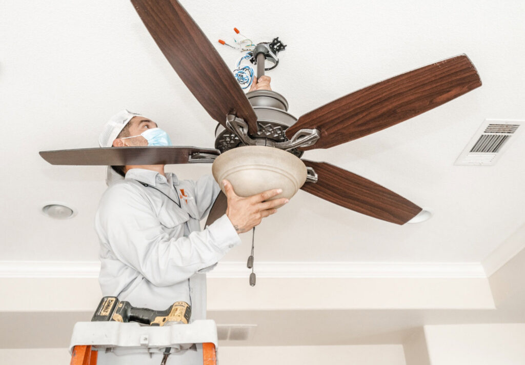 An electrician from 4G Electrician installing a ceiling fan in a residential property in Dallas, TX