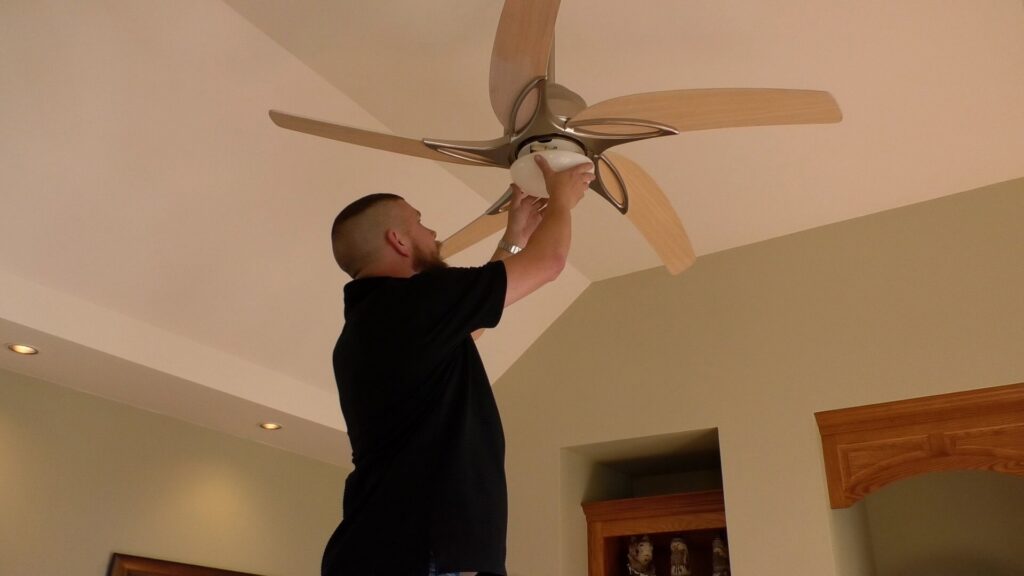 An electrician installing or repairing a ceiling fan in a home for Babcon Electric Inc. in Richmond, KY