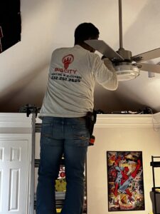 An electrician from Big City Lighting and Electric installing a ceiling fan in a home in Houston, TX.