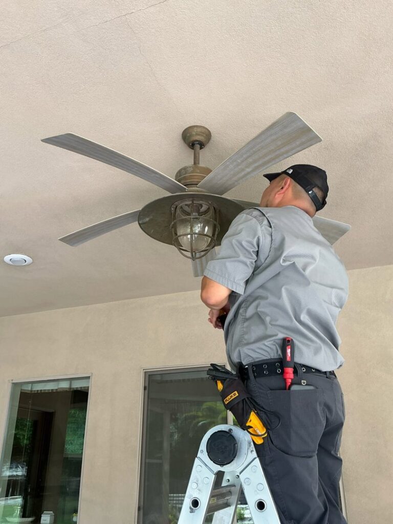 An Electricode electrician on a ladder installing a ceiling fan on an outdoor patio in Las Vegas, NV.