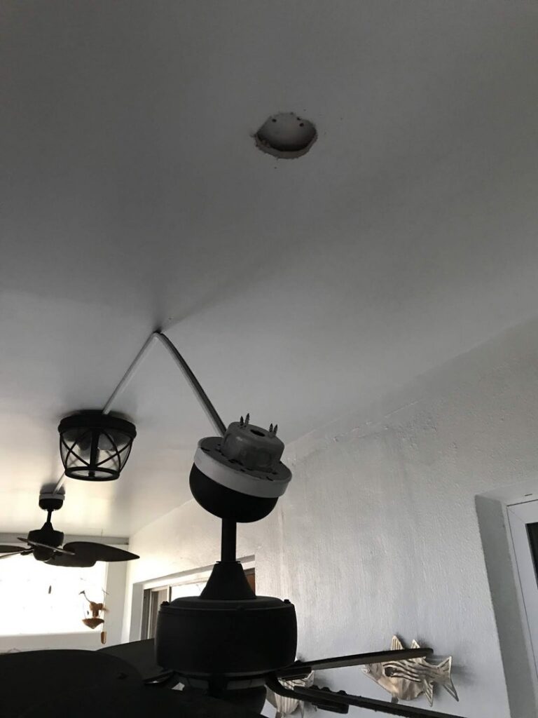 An electrician from Fuller Electrical Contractors, Inc. installing a ceiling fan in Oldsmar, FL.
