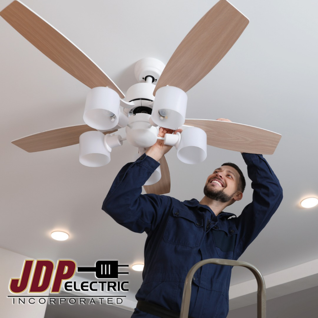 An electrician installing a new ceiling fan with lights at JDP Electric in Fargo, ND.
