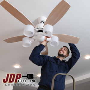 An electrician installing a new ceiling fan with lights at JDP Electric in Fargo, ND.