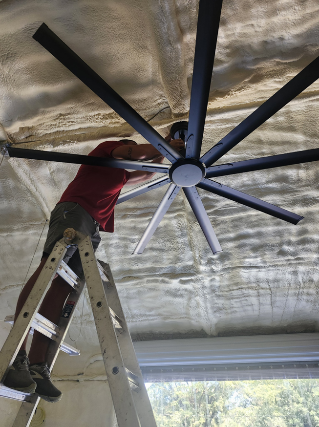 An electrician installing a large ceiling fan for a customer at Steele Electric Service in Forest Grove, OR.