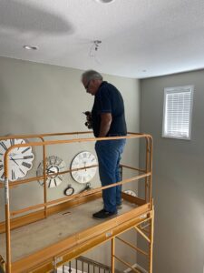 An electrician on scaffolding installing a ceiling light fixture for All Electric llc in Denver, CO