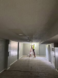 An electrician from Amped Electric installing a ceiling light fixture in Virginia Beach, VA.